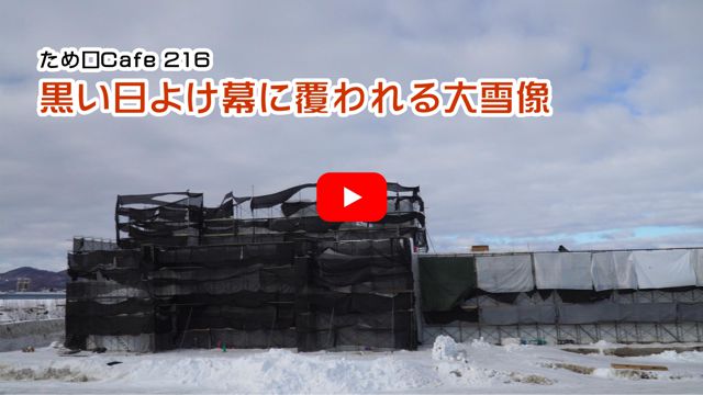 黒い日よけ幕に覆われる大雪像